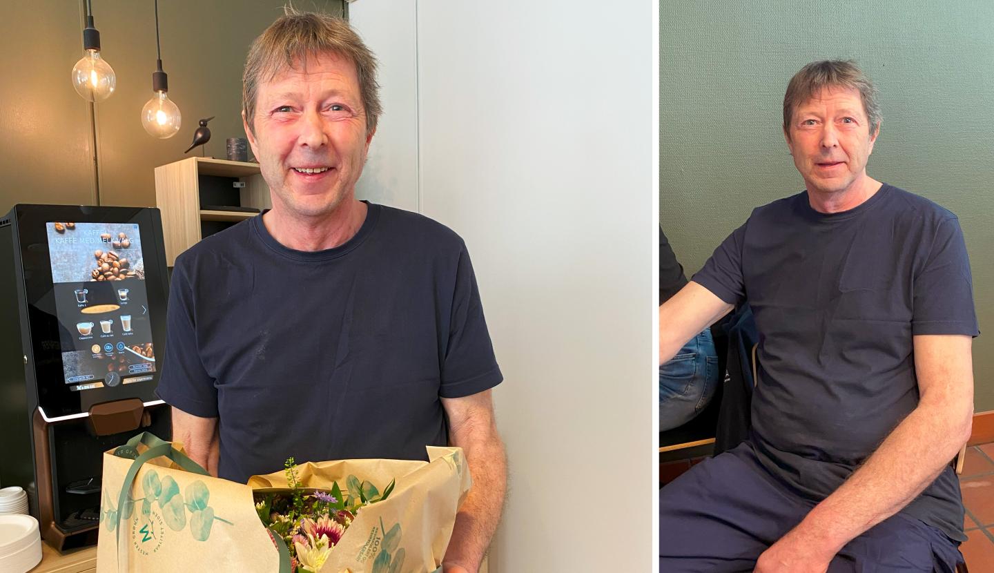 En person holder en blomsterbukett og smiler, på venstre side av bildet, foran en kaffemaskin, med en grønn vegg i bakgrunnen.